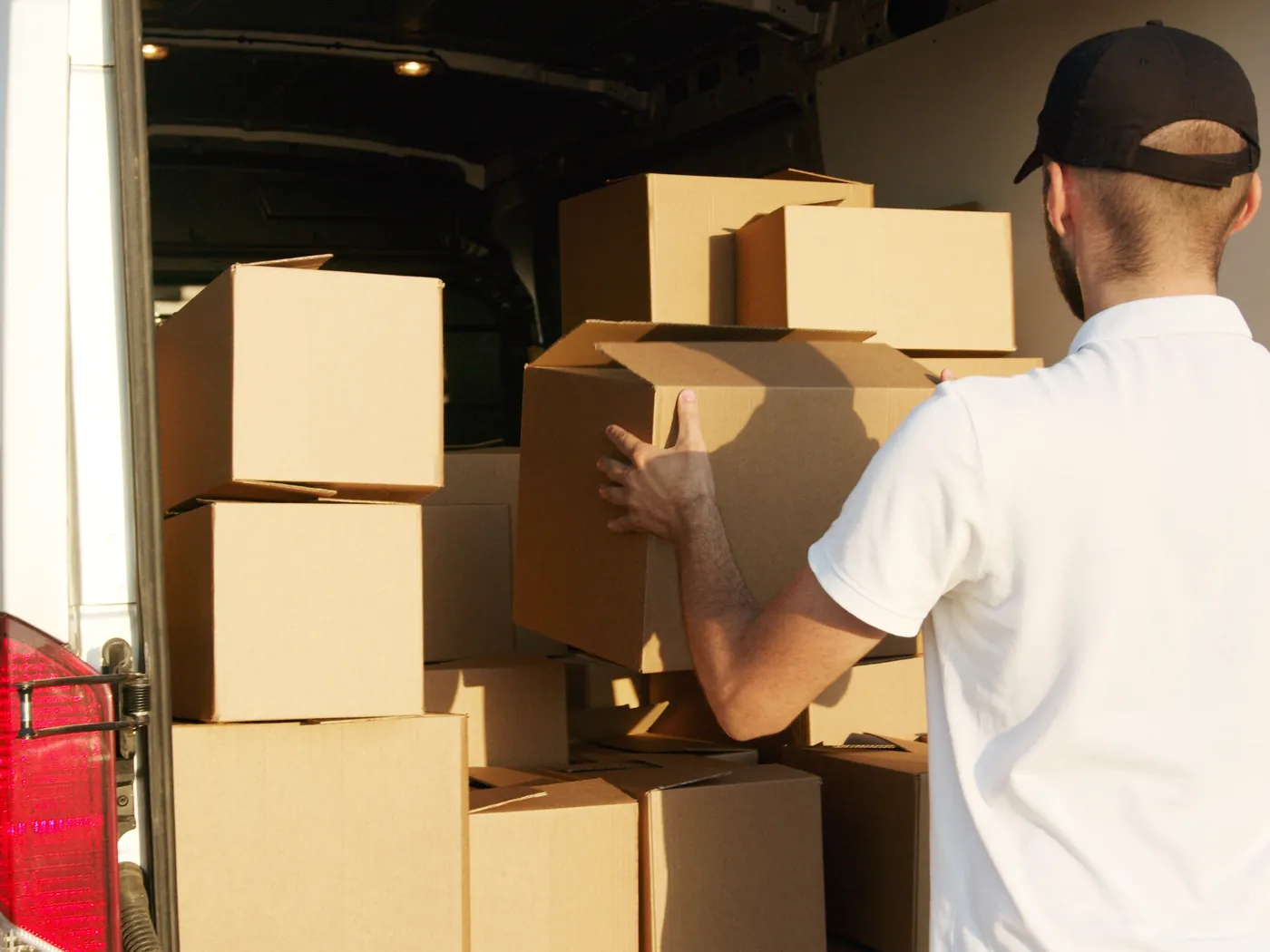 Umzugshelfer stapelt Kartons im Laderaum des Transporters